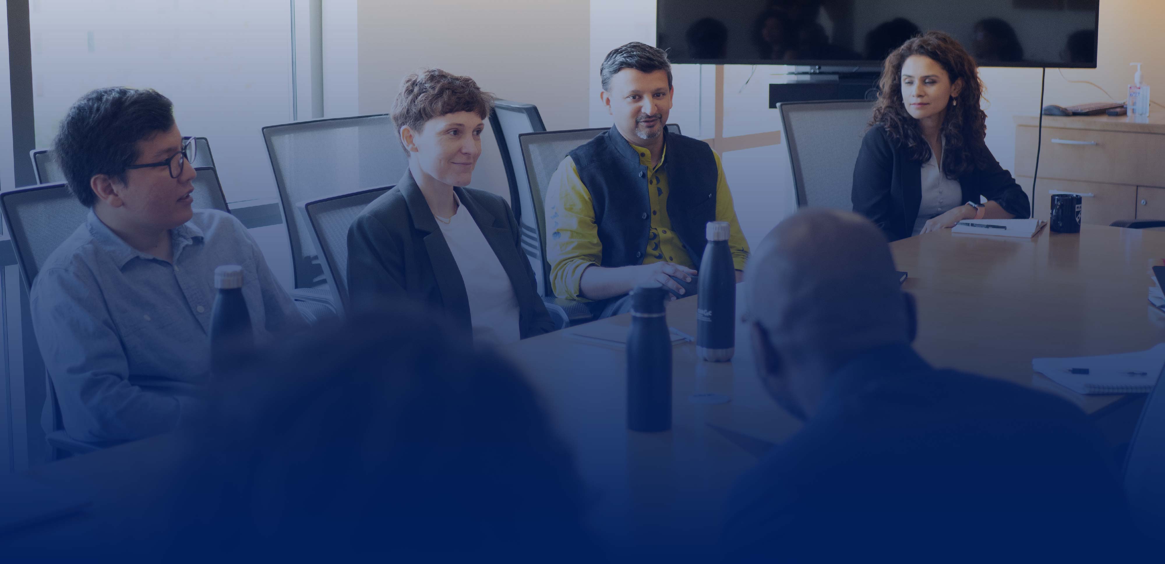 Four people sitting at a conference table and talking
