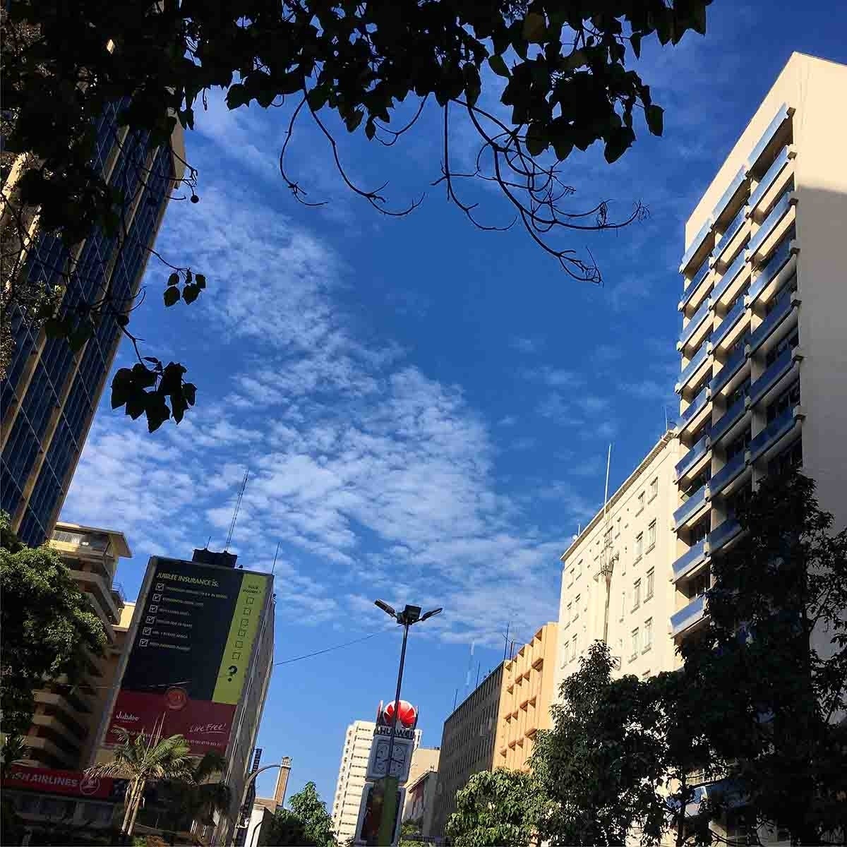 High-rise buildings on the left and right, and a slightly cloudy, blue sky above.