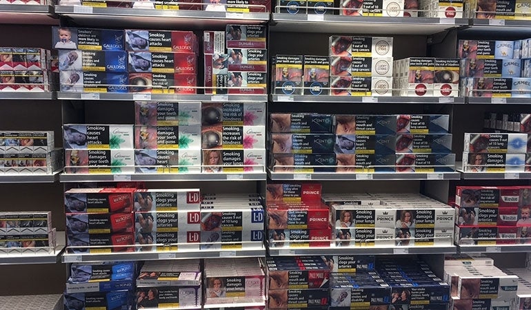 rows of European cigarette packs with pictorial warning labels in a store 