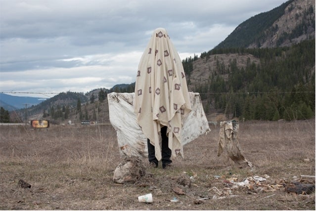 person standing in field in front of mountain range covered in a blanket