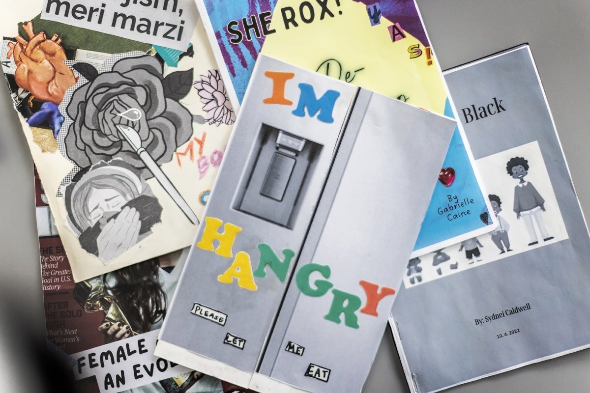 A flatlay of zines. The top one looks like a refrigerator with magnets that read: “I’m hangry. Please let me eat.”