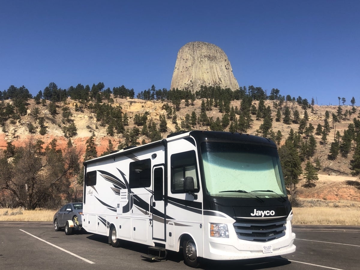 RV in a parking lot with gorgeous desert rock formation in the background