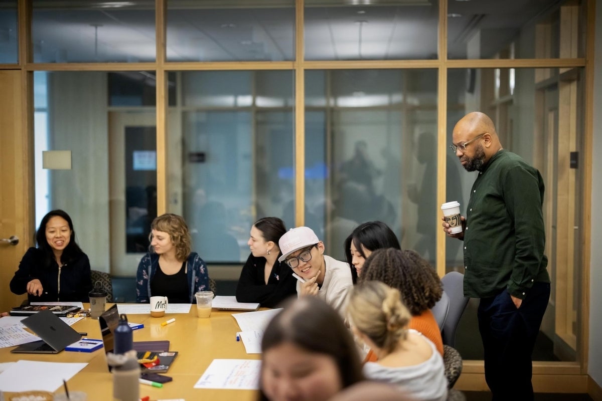 Prof. Desmond Patton watches students draw joy maps at a conference table