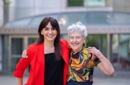 Sandra Gonzalez-Bailon and Carolyn Marvin posing with arms around one another in front of the Walnut St Entrance to the Annenberg School