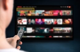 a person pointing a remote at a television with rows of streaming apps