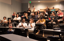 people sit in a classroom watching the Harris v. Trump debate