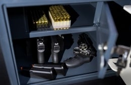 Pistols, revolver and cartridges in a gun safe, close-up photo.