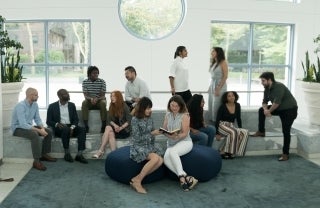 Group of students with dean seated around a large area in the plaza lobby