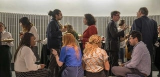 Group of people seated and standing, all talking at a reception