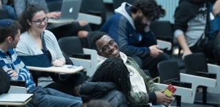 Students seated in classroom desks, smiling and talking