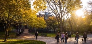 Several people walking on paths in front of College Hall