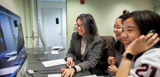 Three students smiling looking at a computer screen