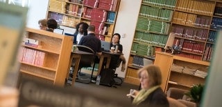 Students working in the Annenberg library with colorful bookshelves behind them