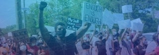 Man holding up sign amid other protestors, photo credit Alex Robinson / Unsplash