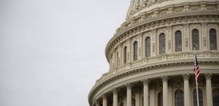 Partial view of the United States Capitol Rotunda. The flag on a pole is in front. Photo by Joshua Sukoff on Unsplash.