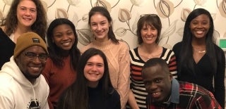 Group of people posing for a photo against floral wallpaper