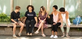 Five students sitting outside and laughing