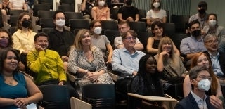 Group of people sitting in an auditorium, seemingly listening to someone