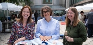 Three staff members smiling at the camera at an outdoor event 