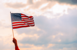 a U.S. flag being held in the air against a blue sky