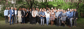 Group picture of the 2024 Milton Wolf Seminar attendees in a yard in front of trees.