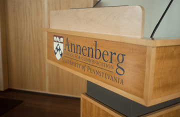 close shot of a wooden podium with the words "Annenberg School for Communications" on the front