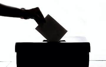 Photo of a hand dropping a ballot into a voting box. Photo credit: Element5 Digital / Unsplash