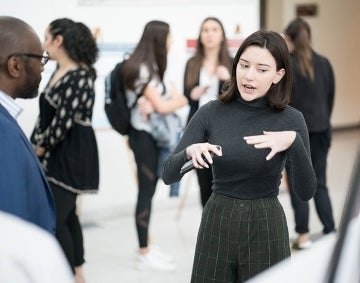 Student speaking while gesturing amid a group of other students