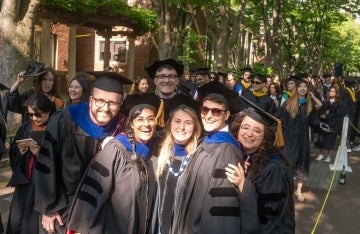 A group of graduates in regalia posing on Locust Walk