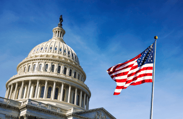 Top of the Capitol Building in Washington D.C. with a waving U.S. flag