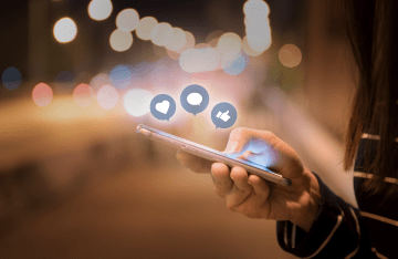 A person using a smartphone with an animation of social media likes and hearts