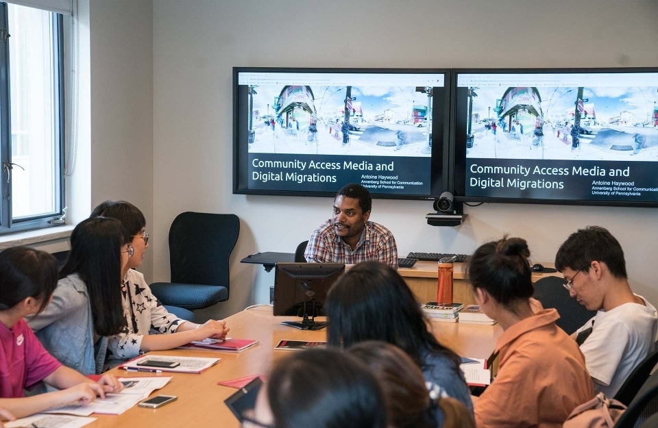 Antoine Haywood seated at the head of the table with students on either side looking at him