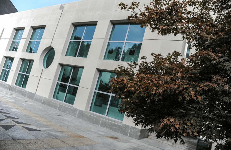 slanted view of the Annenberg School covered a bit on the right with fall tree leaves