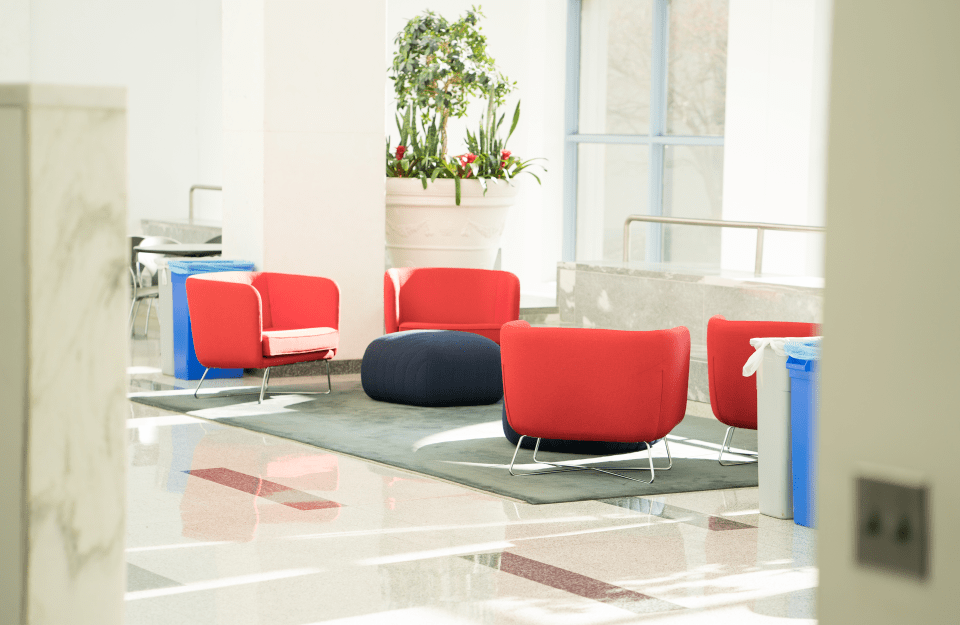 view of a white room with red chairs, white tiles, and a large potted plant 