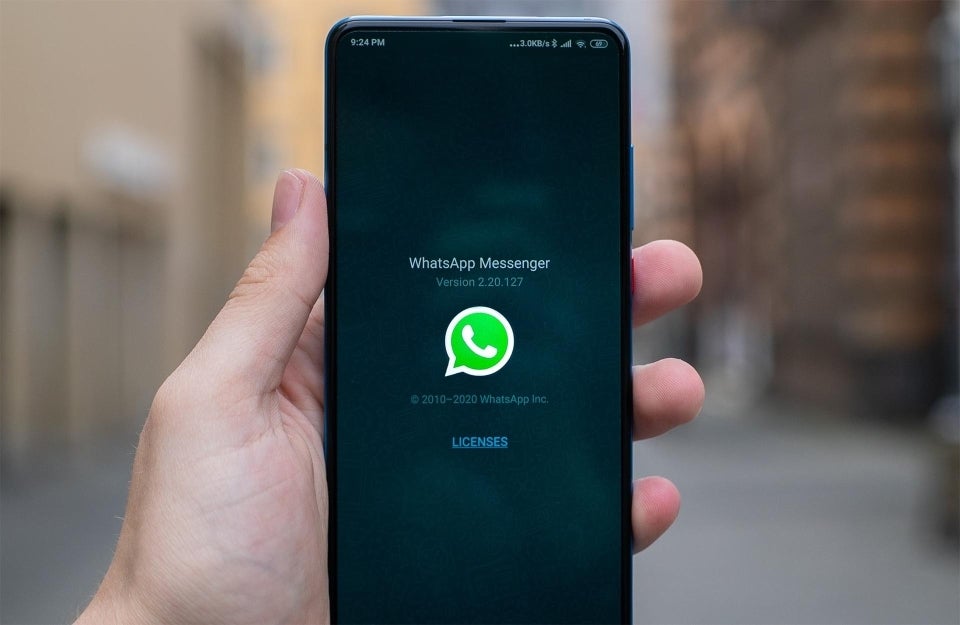 Smartphone against blurred background with WhatsApp logo displayed on the screen; photo credit: Mika Baumeister / Unsplash