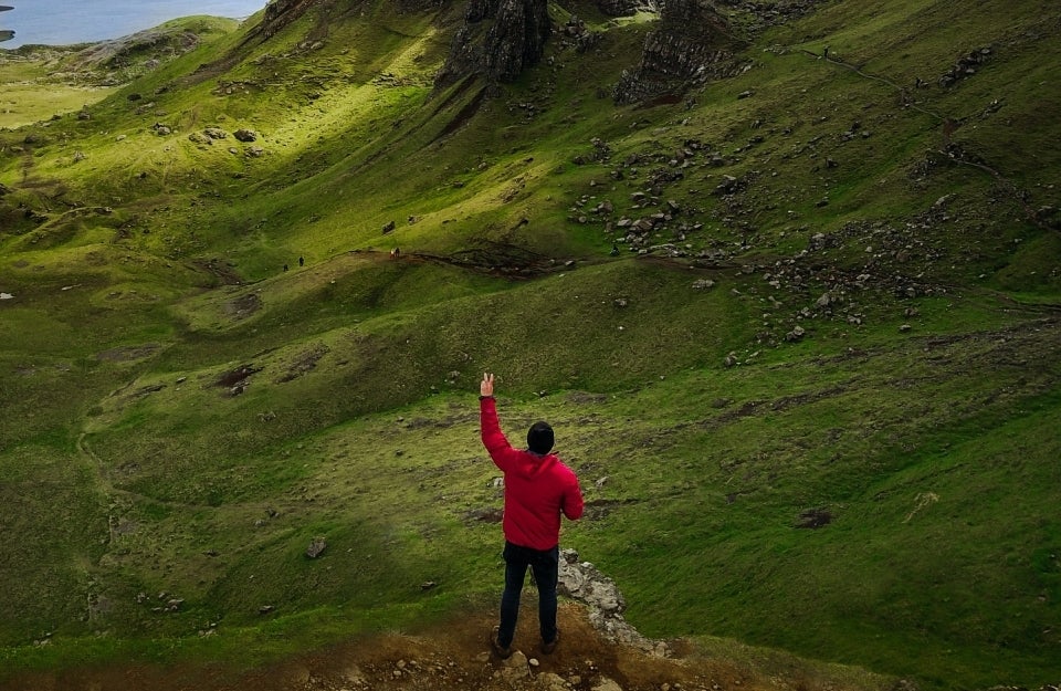 man standing in nature with his left hand up, making a peace sign, photo credit Michael Block/Pexels