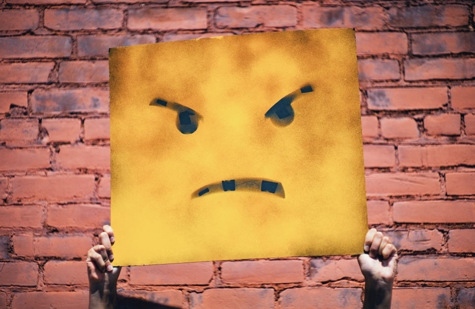 Two hands holding up a sign with an angry face illustration, Photo Credit: Andre Hunter / Unsplash