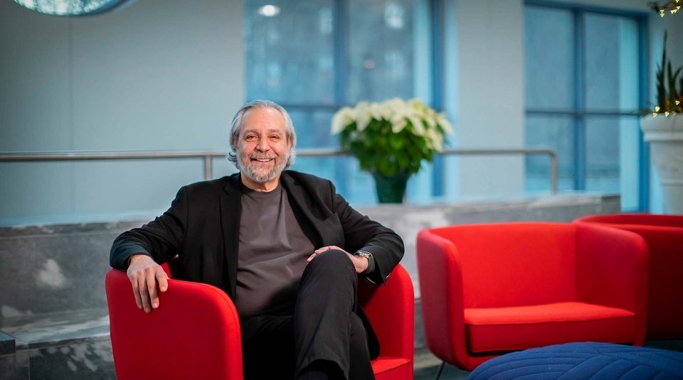 Michael Delli Carpini seated in a red chair in the marble Plaza Lobby