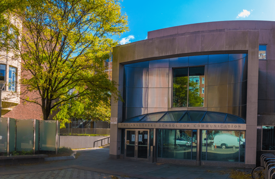 The facade of the Annenberg building surrounded by trees with green leaves