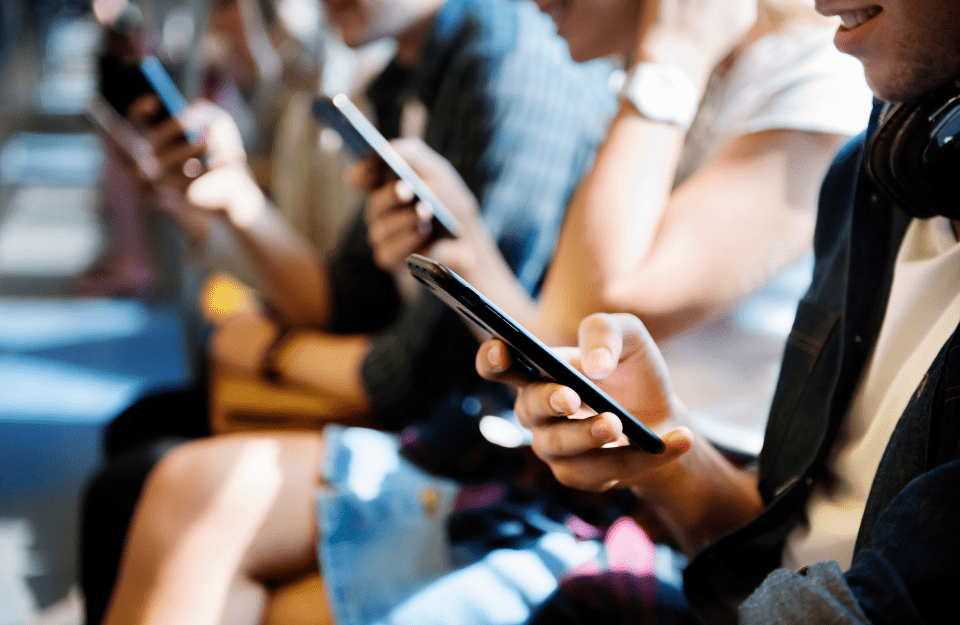 People sitting side by side holding and looking down at smartphones