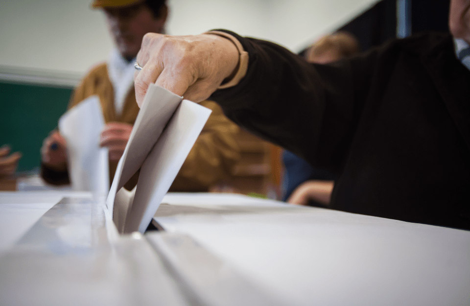 conceptional image of a person dropping a ballot into a ballot box