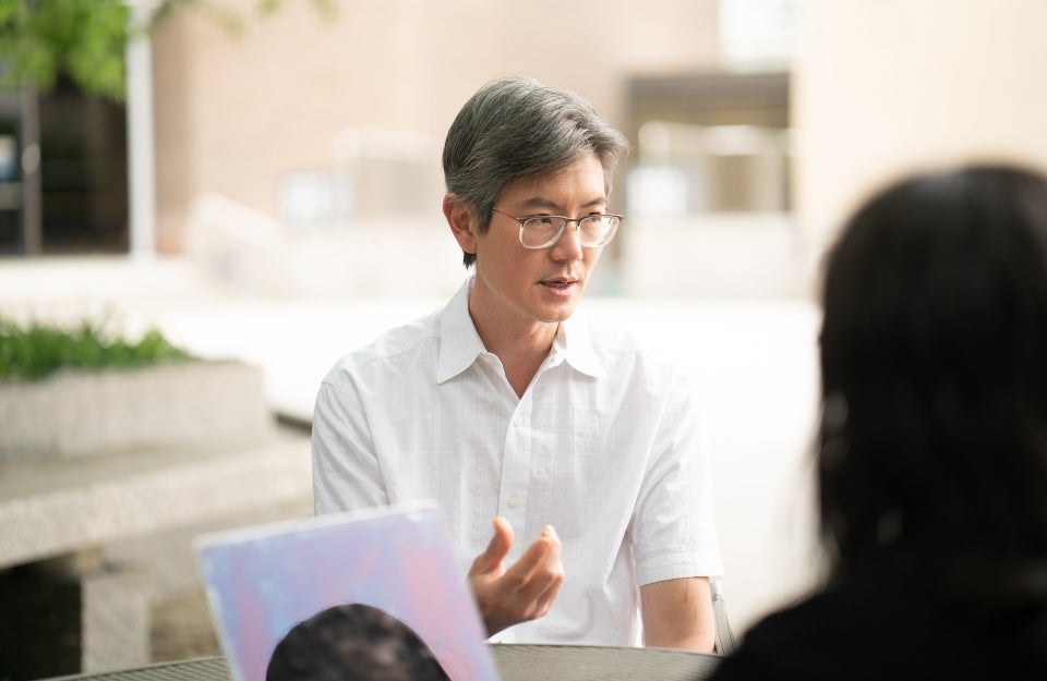 Andy Tan sits outside talking to students