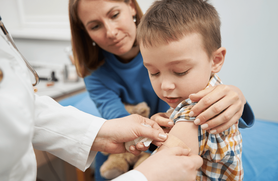 Doctor placing a bandage on a child's arm after vaccination