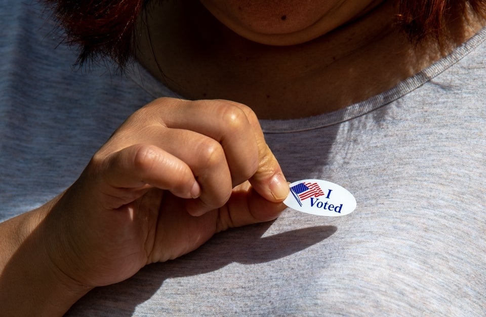 Person sticking an "I Voted" sticker to their shirt