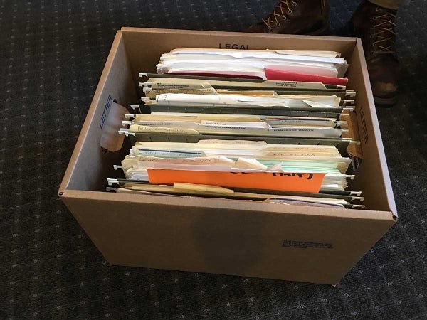 An overhead shot of an opened records box. It is filled with file folders of different colors.