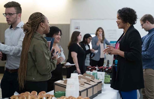 Shawnika Hull speaking to students over a table of food, with other students in the background