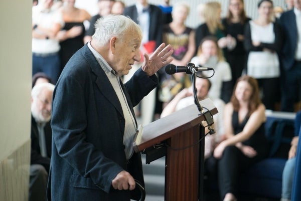 Elihu Katz speaking at a podium with an audience in the background