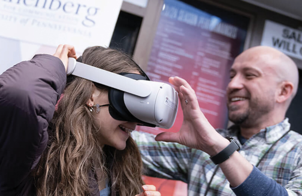 A man helping a woman put on a VR headset