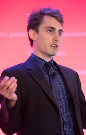 Guilbeault delivering talk against pink background