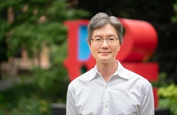 Andy Tan smiling standing outdoors in front of the LOVE status on Penn's campus